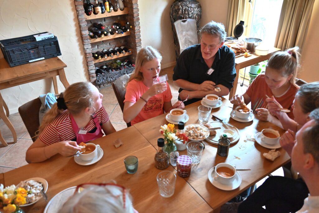 3 kinderen en een oudere man zitten aan tafel bij evenement Kleurrijk koken als onderdeel van Wiede Wold.