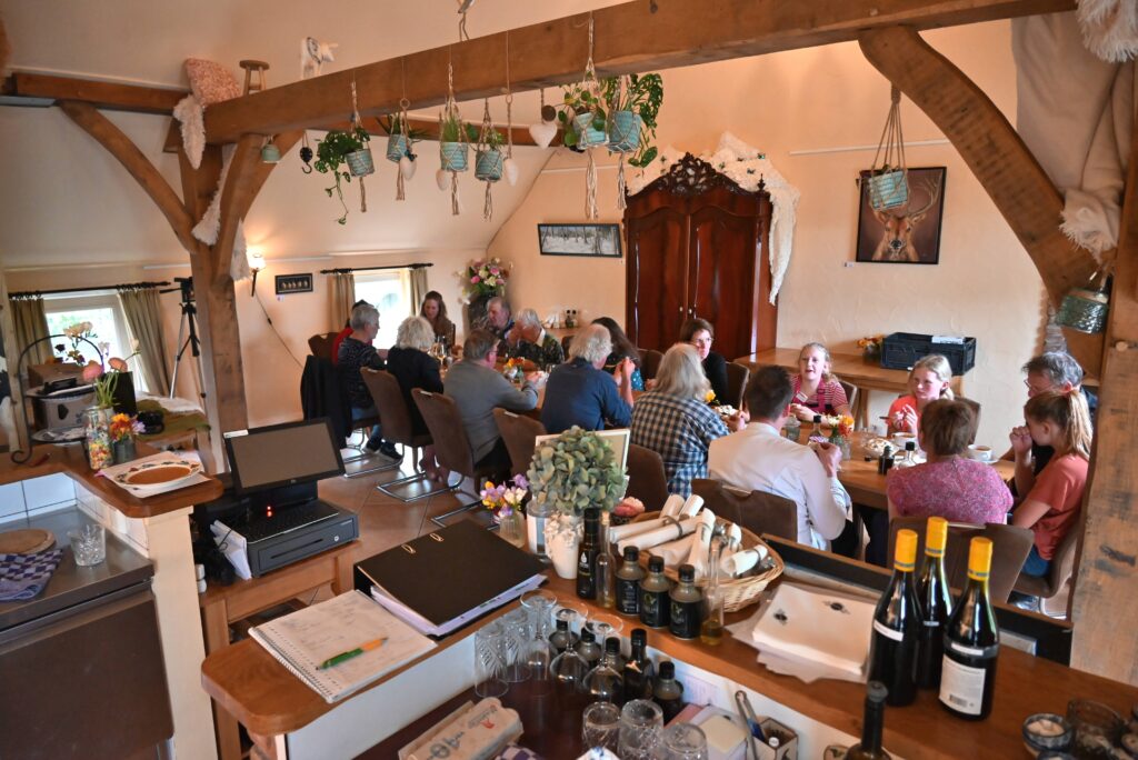 Een groep mensen zit aan tafel van het evenement Kleurrijk koken van Wiede Wold. 