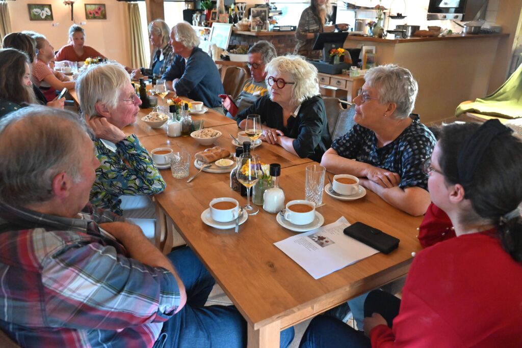 Een groepje mensen zitten samen aan tafel een kopje tomatensoep te eten als onderdeel van het evenement Kleurrijk Koken, van Wiede Wold